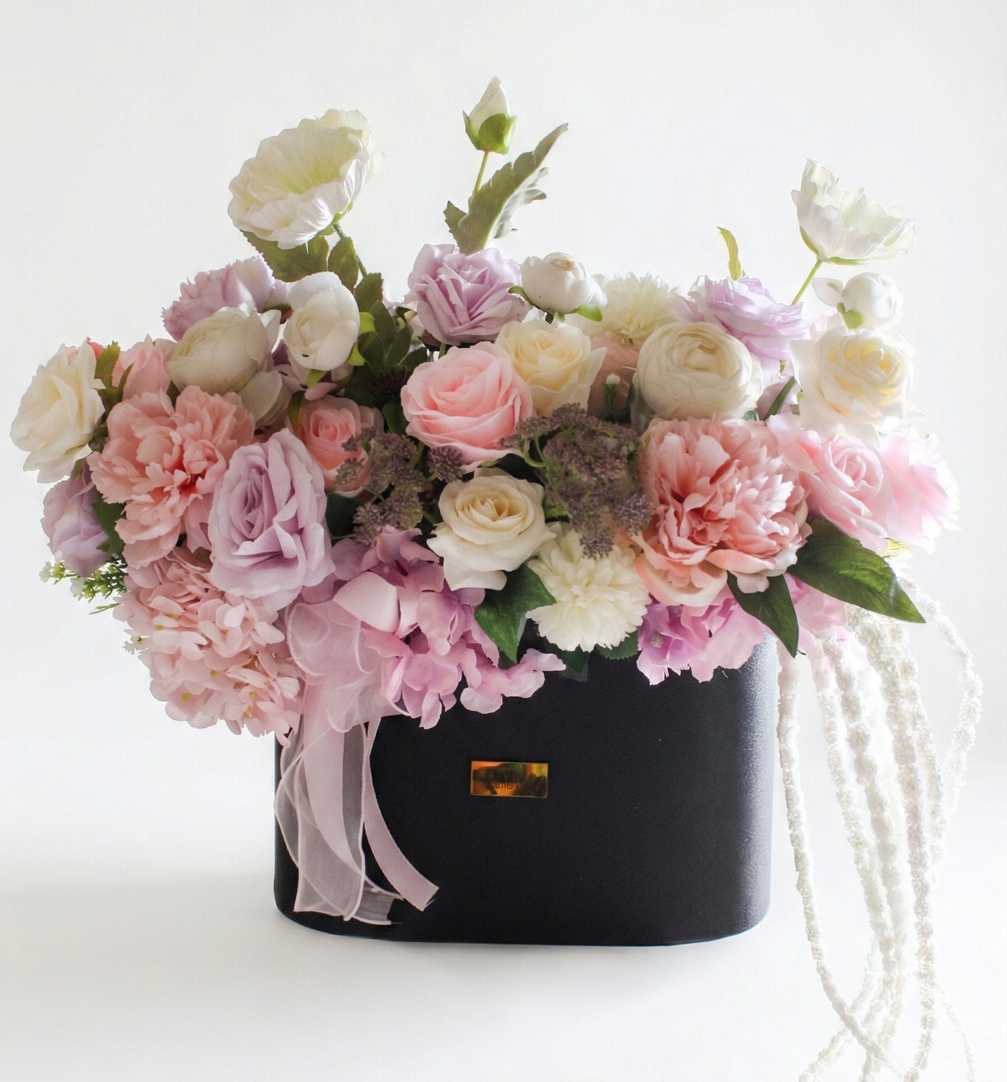 Black handbag with pink and white flowers on a white background
