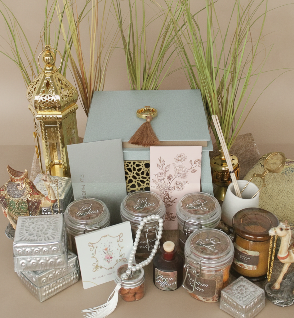 Collection of decorative items including jars, boxes, and a lamp on a table with plants in the background.