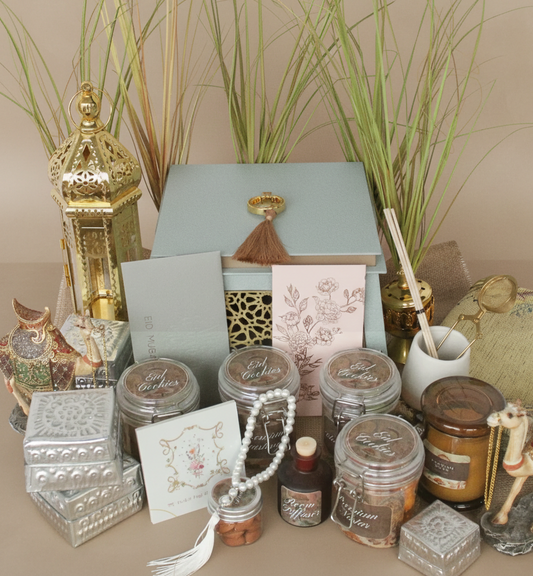 Collection of decorative items including jars, boxes, and a lamp on a table with plants in the background.