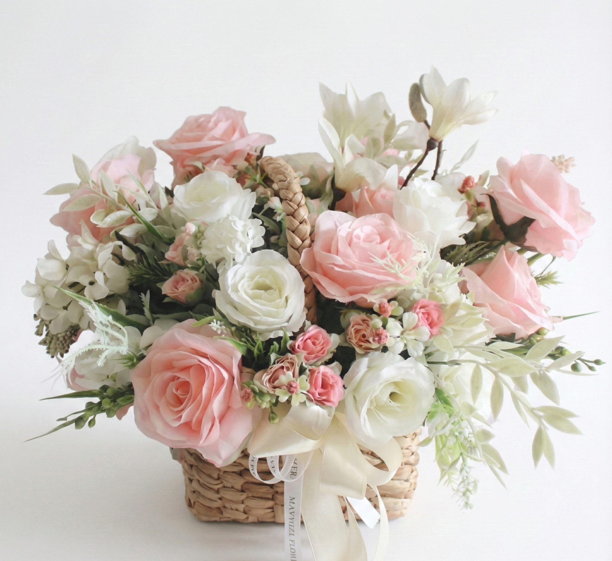 Bouquet of pink and white flowers in a woven basket on a light background