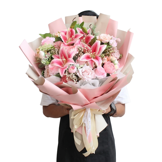 Bouquet of pink flowers with ribbons held by a person on a white background