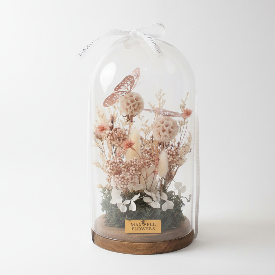 Glass dome with dried flowers and a butterfly, branded 'Maxwell Flowers', on a white background