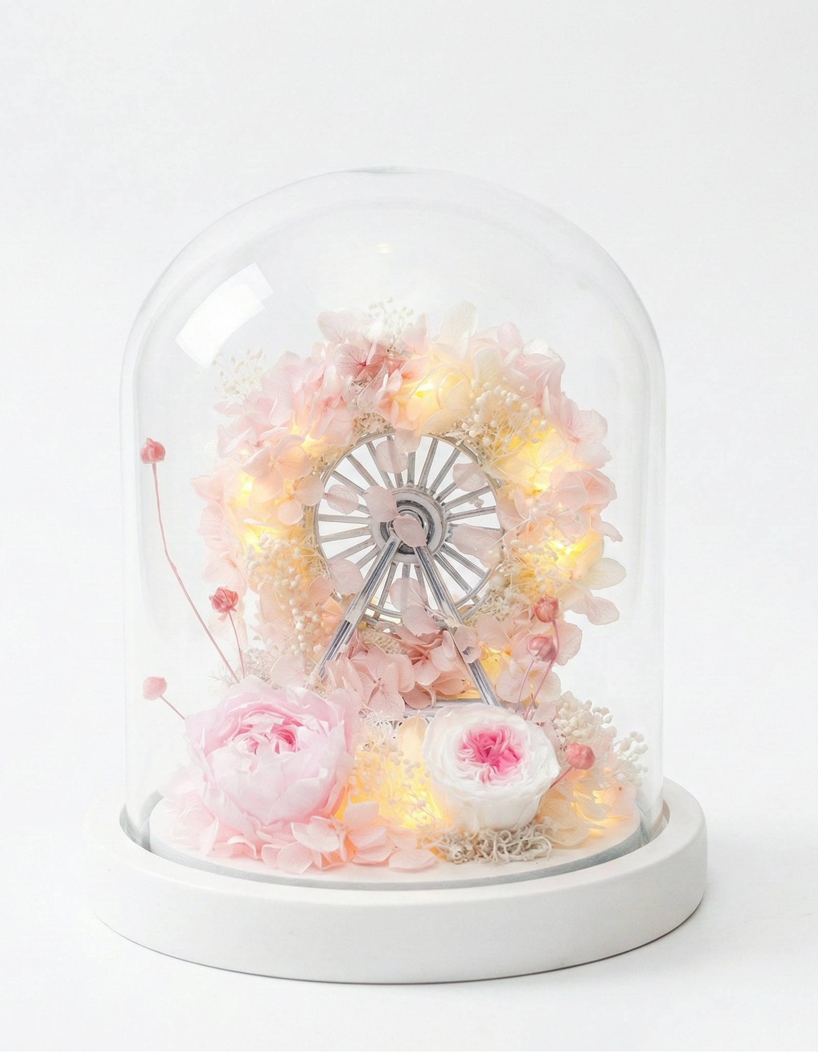 Decorative glass dome with fairy lights and flowers on a white background