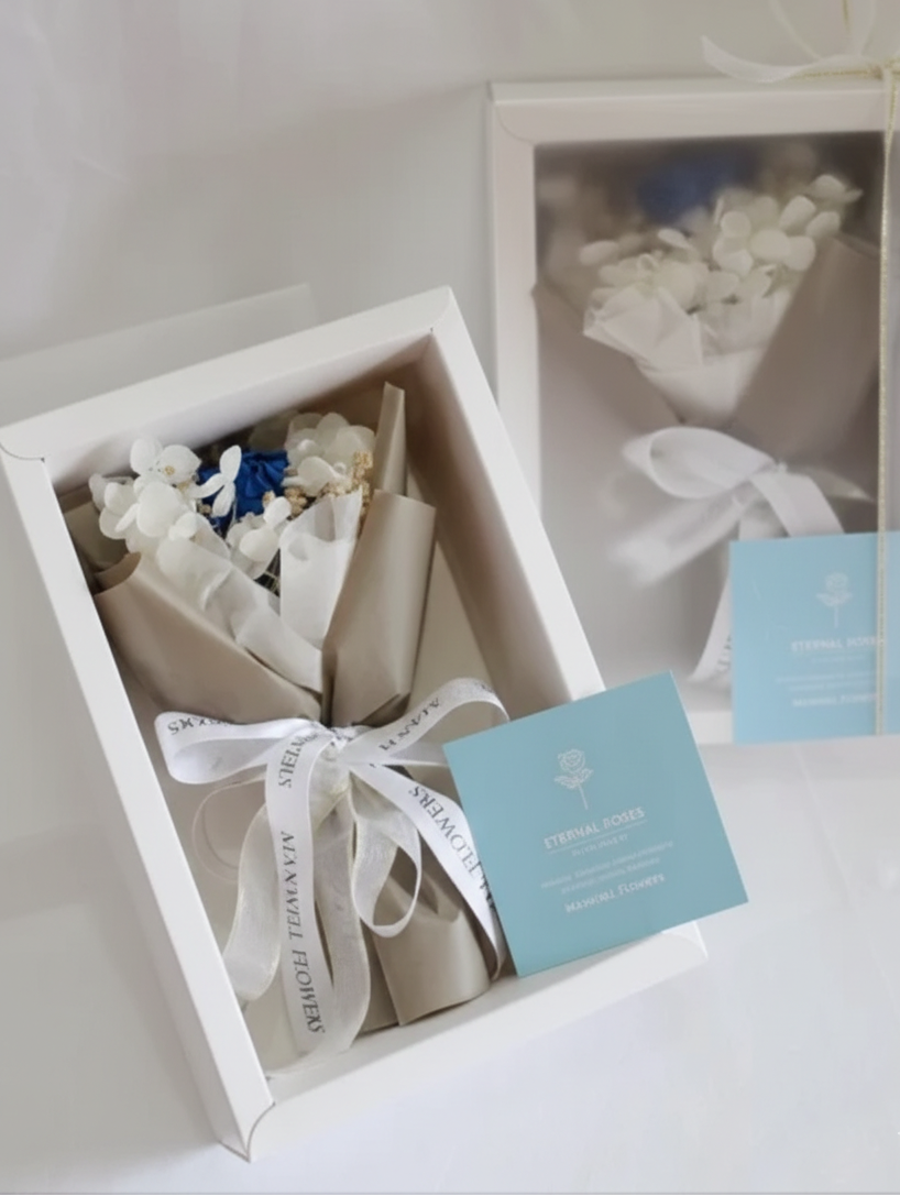 Gift box with a bouquet of flowers and a card on a white surface