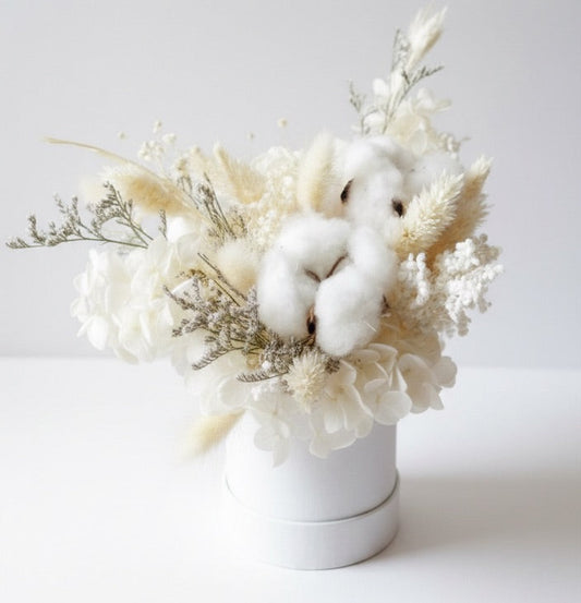 Bouquet of white flowers and cotton in a white vase on a light gray background