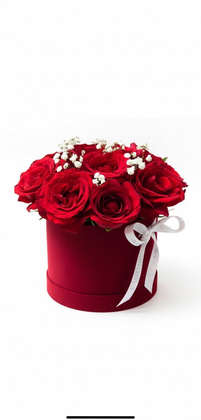Red flowers in a box with a white ribbon on a white background