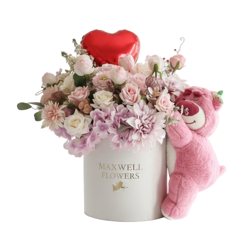 Floral arrangement with a heart, teddy bear, and 'Maxwell Flowers' box on a white background
